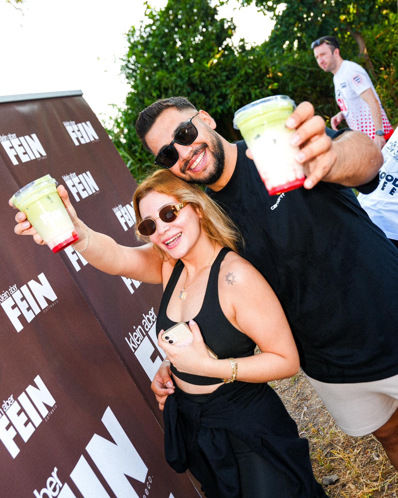 Klein aber FEIN panosu önünde matcha latte kaldırıp gülen iki misafir